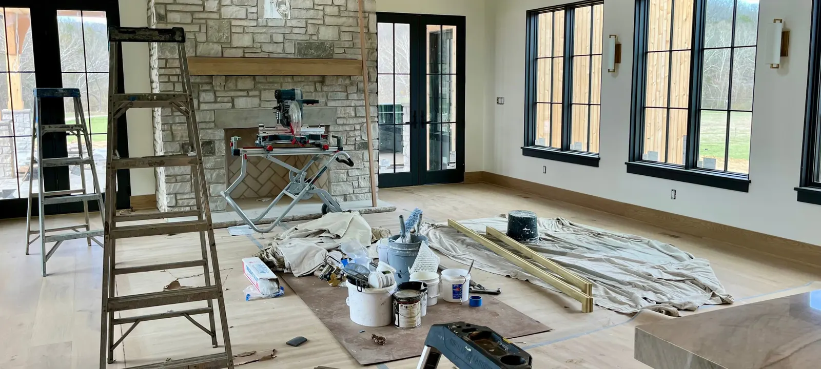 Ladders, paint cans, drop cloths, saw on the floor