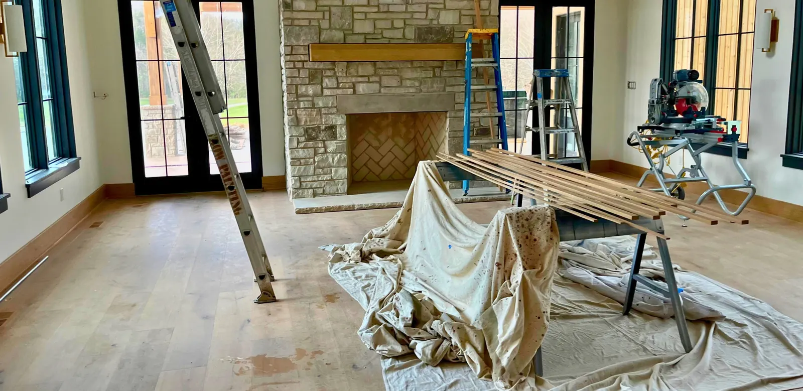 Great room mid-construction with ladders and drop cloths